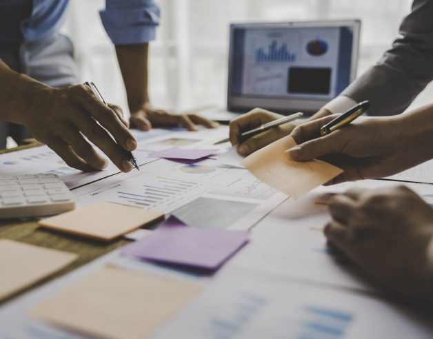 Financial analyst analyzes business finance reports on laptop and graph documents during corporate meeting discussions showing successful teamwork, business meeting ideas, marketing.